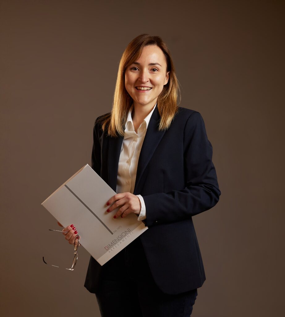Laura adetta all'amministrazione in Dimensioni con in mano gli occhiali e una cartella di lavoro